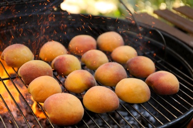 Photo of Modern grill with tasty juicy peaches outdoors, closeup