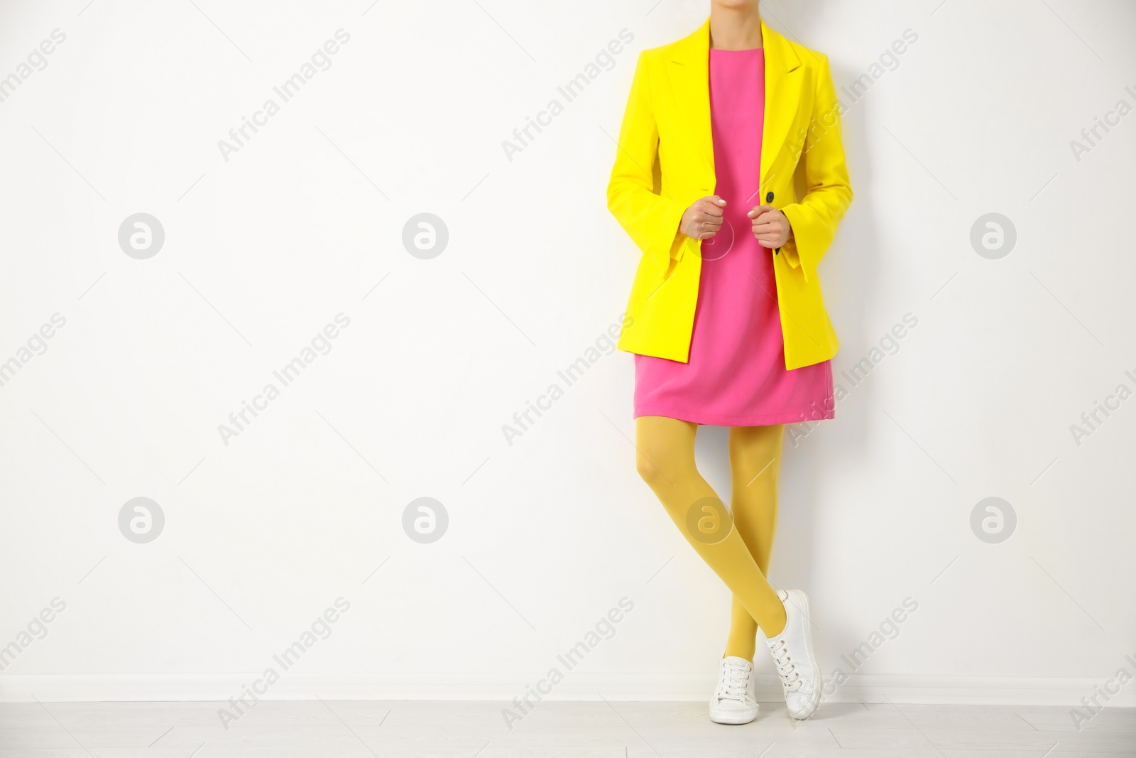 Photo of Woman wearing yellow tights near white wall, closeup. Space for text