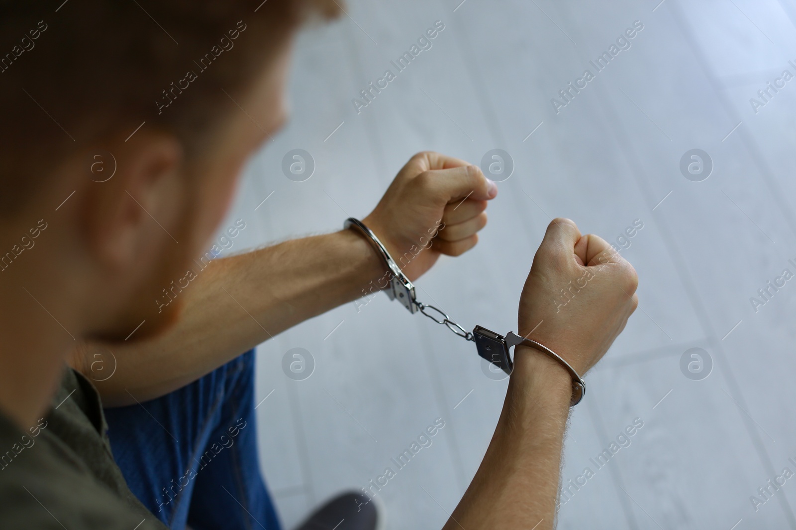 Photo of Man detained in handcuffs indoors, closeup view. Criminal law