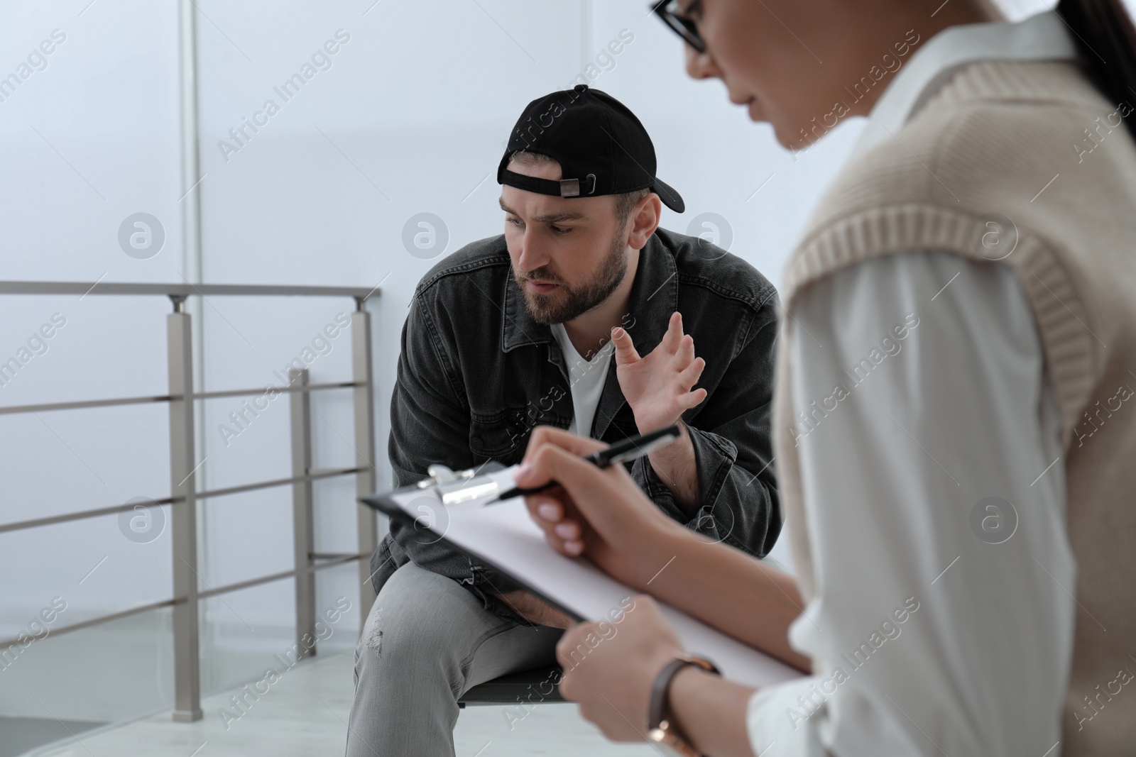 Photo of Psychotherapist working with drug addicted young man indoors