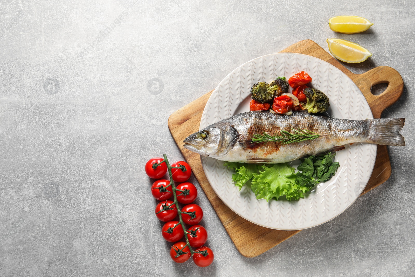 Photo of Delicious baked fish and vegetables on light grey table, top view. Space for text