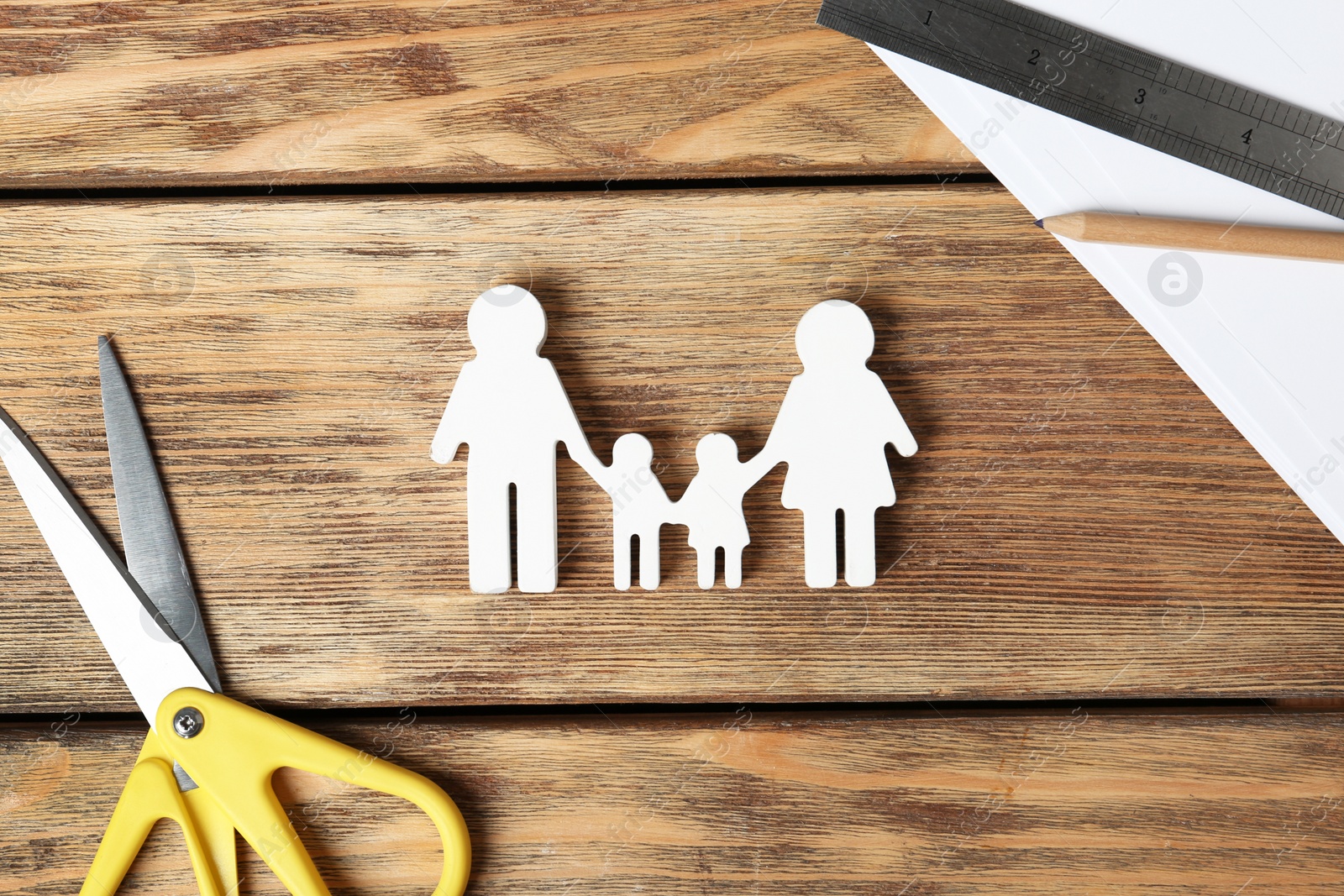 Photo of Flat lay composition with family figure and scissors on wooden background. Life insurance concept