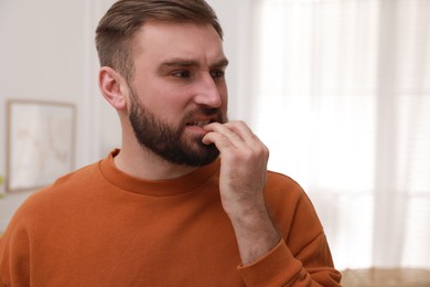 Photo of Man biting his nails indoors, space for text. Bad habit