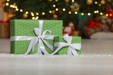 Gift boxes on floor near Christmas tree in room, space for text