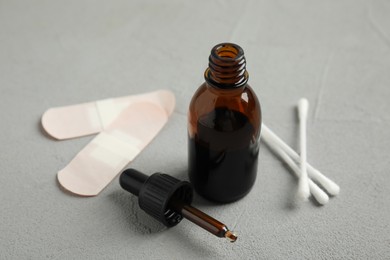 Bottle of medical iodine, cotton buds and sticking plasters on grey table