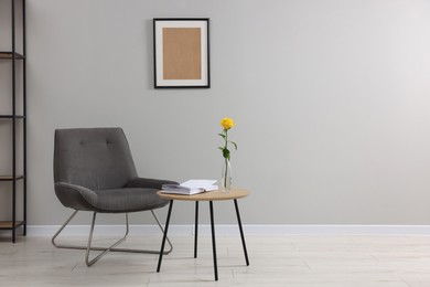 Photo of Comfortable armchair and coffee table near light grey wall indoors, space for text. Interior design
