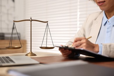 Notary with clipboard writing notes at workplace in office, closeup