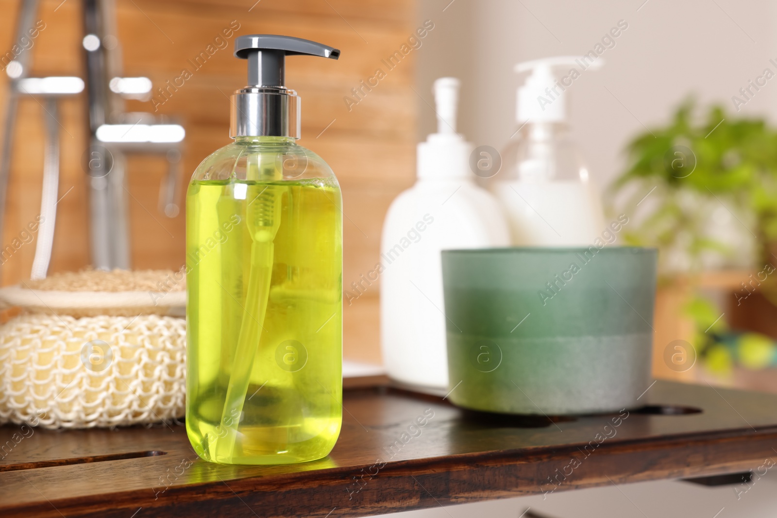 Photo of Dispenser of liquid soap on wooden board in bathroom