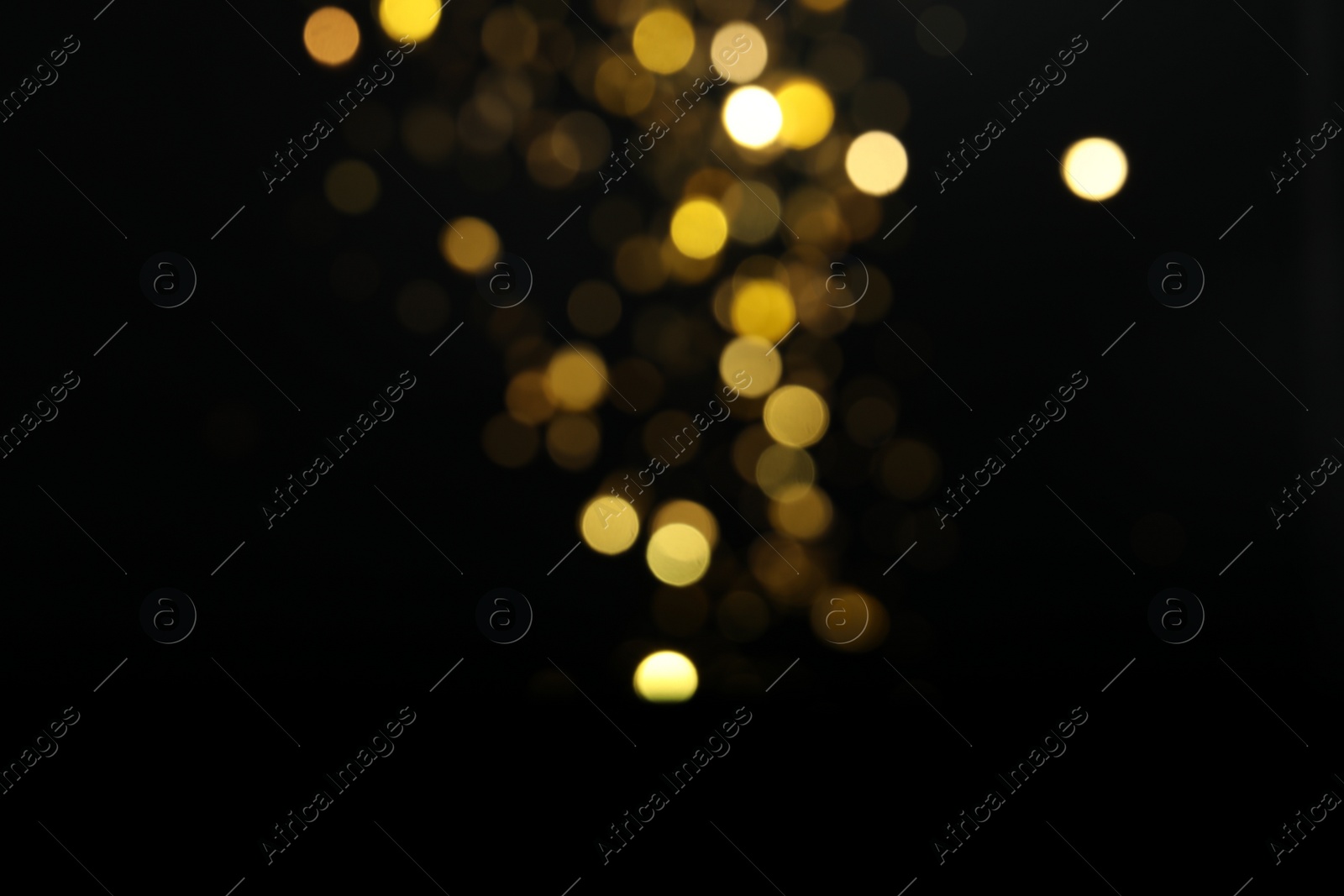 Photo of Blurred view of golden lights on black background. Bokeh effect