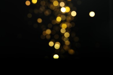 Blurred view of golden lights on black background. Bokeh effect