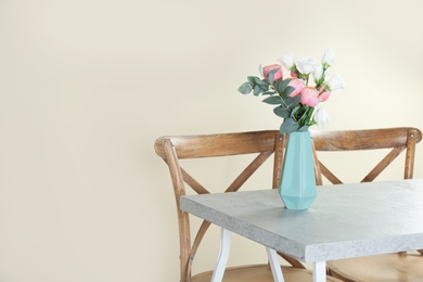 Vase with beautiful flowers as element of interior design on table in room. Space for text