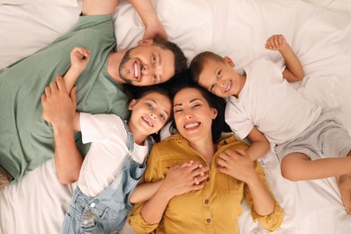 Photo of Happy family with children having fun on bed, top view
