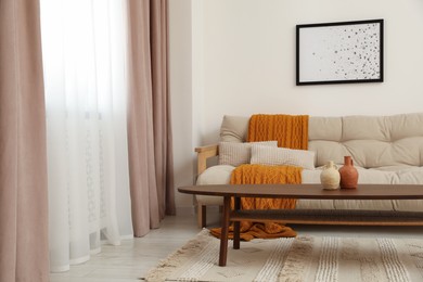 Photo of Living room with pastel window curtains, wooden table and sofa