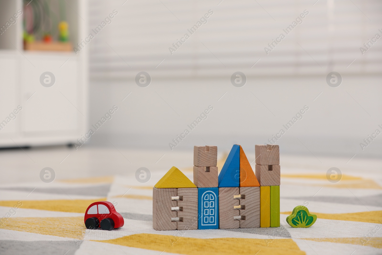 Photo of Set of wooden building blocks on floor indoors, space for text. Children's toys