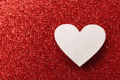 Photo of White wooden heart on red shiny background, top view. Space for text