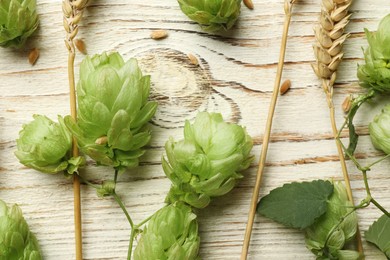 Photo of Flat lay composition with fresh green hops and wheat ears on white wooden table