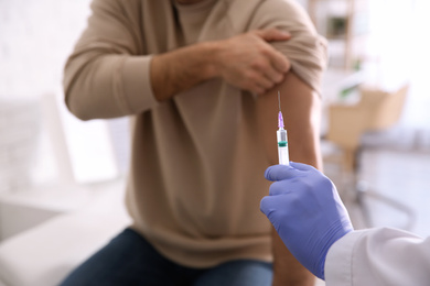 Doctor giving injection to patient in hospital, closeup. Vaccination concept