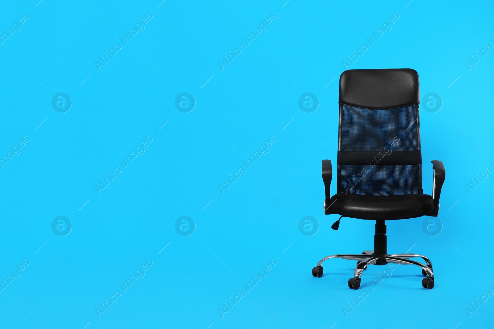 Photo of Comfortable office chair on light blue background, space for text