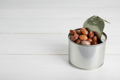 Photo of Tin can with kidney beans on white wooden table, space for text