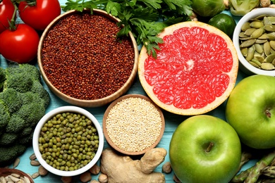 Fresh vegetables, fruits and seeds on light blue wooden table, flat lay