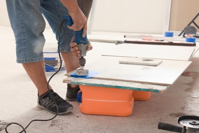 Worker making socket hole in tile indoors, closeup