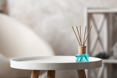 Reed air freshener on white table indoors, space for text