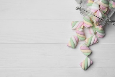 Glass jar with colorful marshmallows on white wooden table, flat lay. Space for text