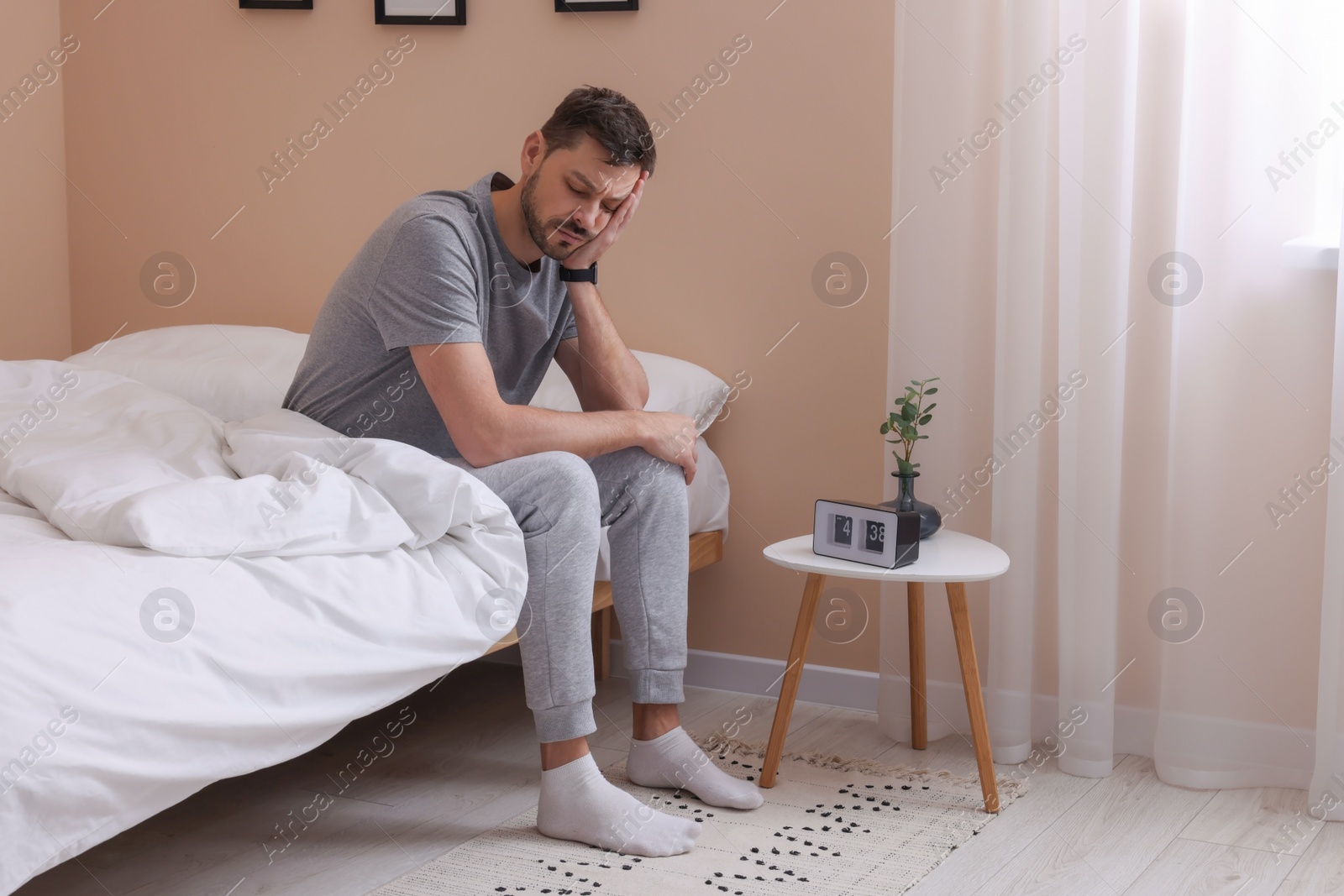 Photo of Sleepy man sitting on bed at home