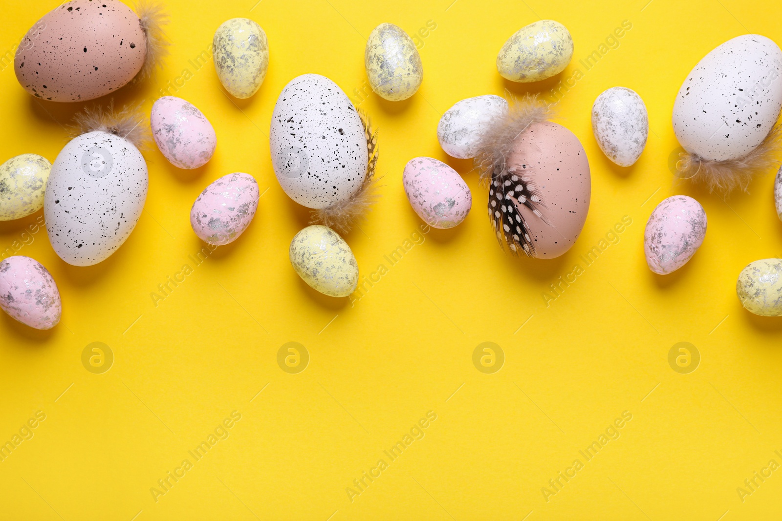 Photo of Many painted Easter eggs on yellow background, flat lay. Space for text