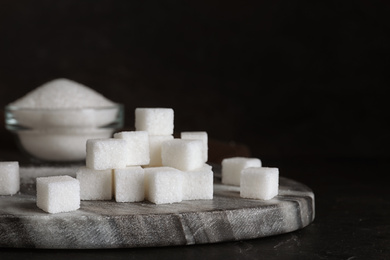 Photo of Heap of refined sugar cubes on black background