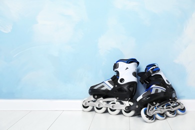 Inline roller skates on floor near color wall. Space for text