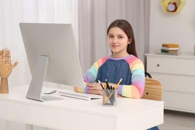 Photo of Cute girl using computer at desk in room. Home workplace