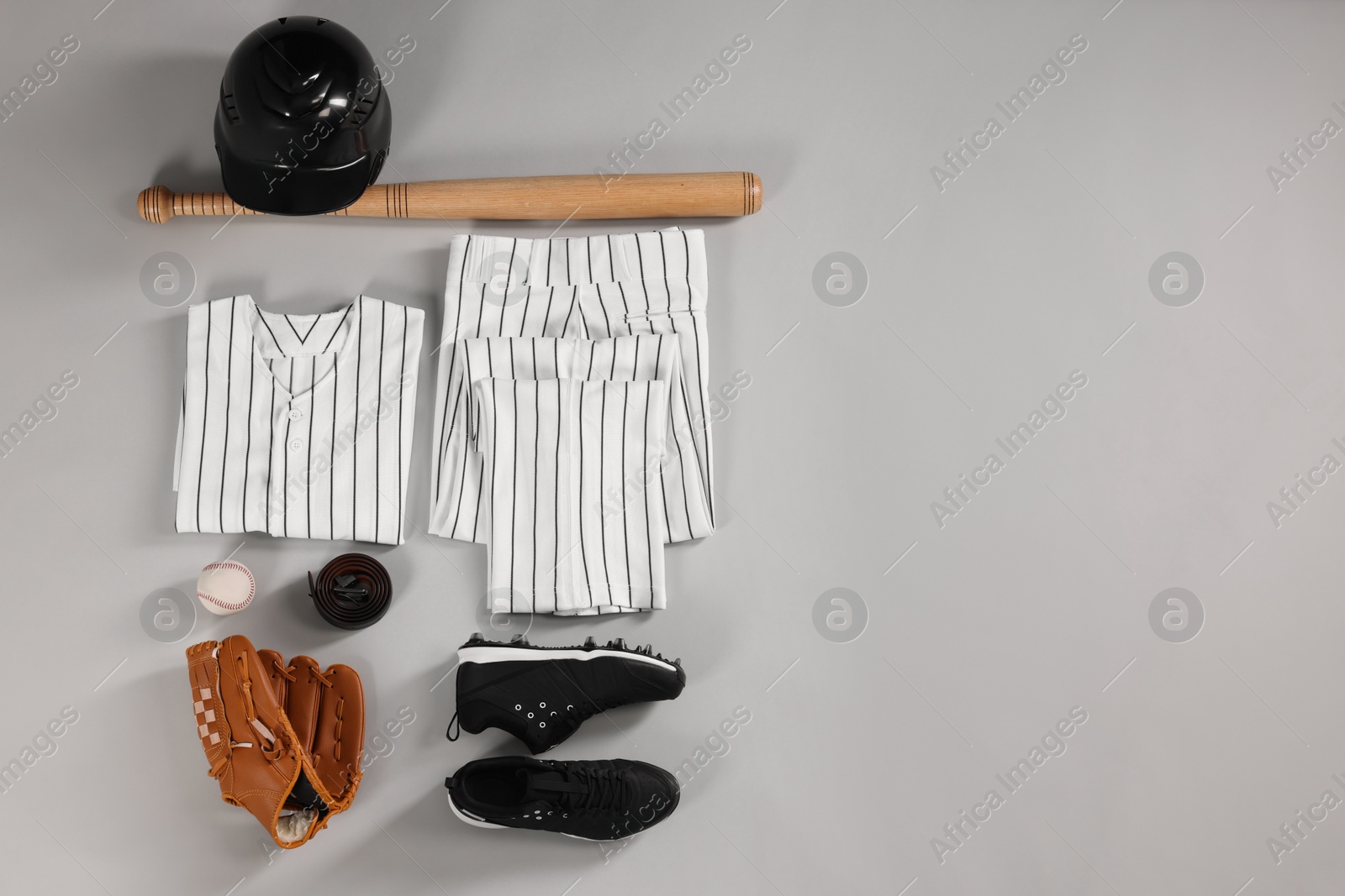 Photo of Baseball uniform and other sports equipment on white background, flat lay. Space for text