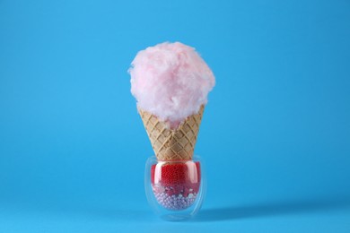 Photo of Sweet cotton candy in waffle cone on light blue background