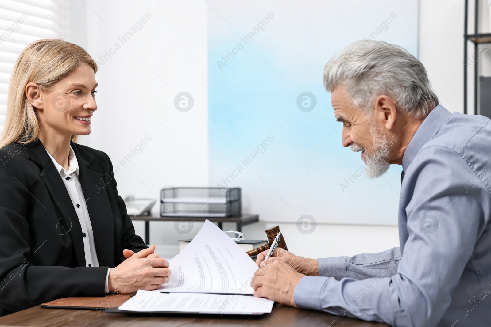 Photo of Senior man signing document in lawyer's office