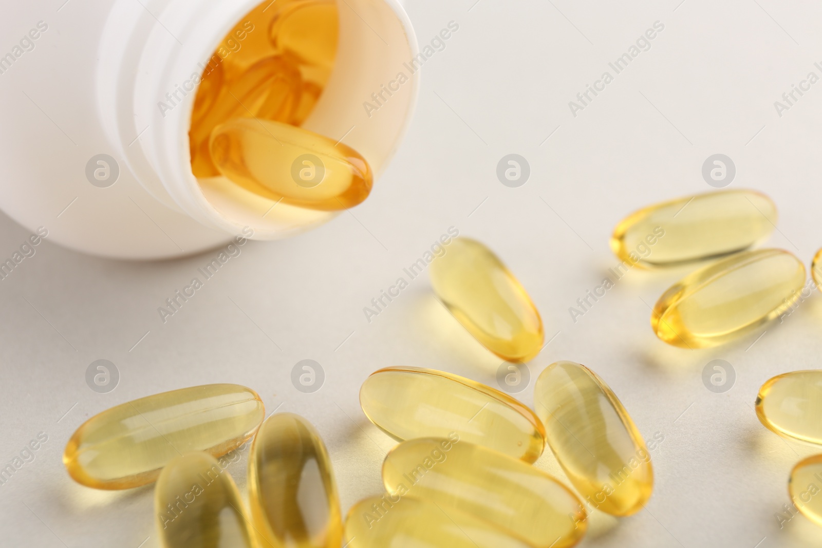 Photo of Vitamin capsules and bottle on light grey background, closeup