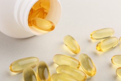 Vitamin capsules and bottle on light grey background, closeup