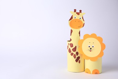 Photo of Toy giraffe and lion made from toilet paper hubs on white background, space for text. Children's handmade ideas