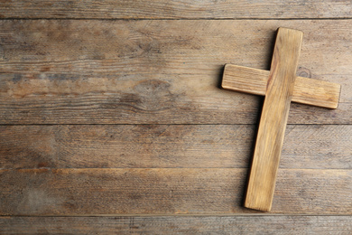 Christian cross on wooden background, top view with space for text. Religion concept