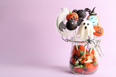Photo of Delicious Halloween themed cake pops on pink background, space for text