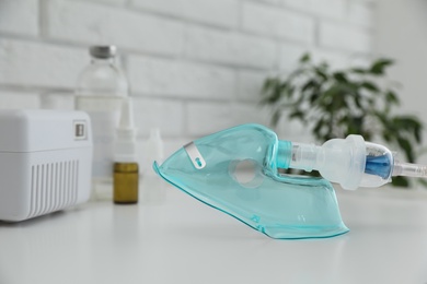 Photo of Face mask of modern nebulizer on white table. Equipment for inhalation