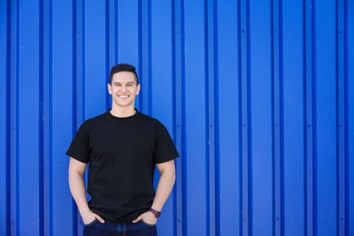 Photo of Young man in black t-shirt near color wall. Mockup for design