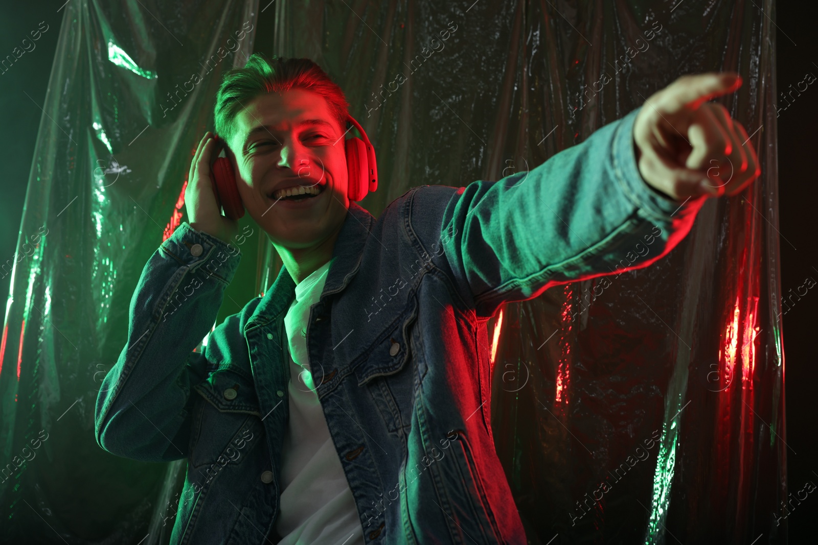 Photo of Young man with headphones dancing in neon lights