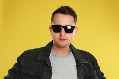 Photo of Young man wearing sunglasses on yellow background