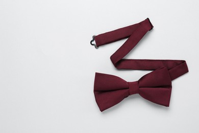 Photo of Stylish burgundy bow tie on white background, top view. Space for text