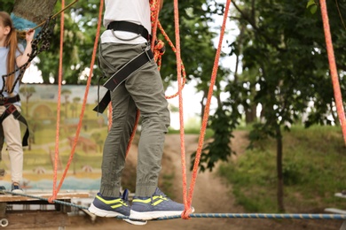 Photo of Little boy climbing in adventure park, closeup. Summer camp