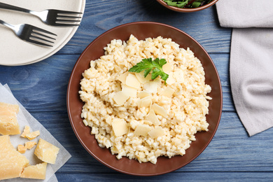 Photo of Delicious risotto with cheese on blue wooden table, flat lay