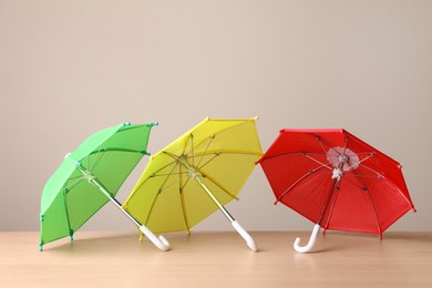 Photo of Small color umbrellas on wooden table against beige background