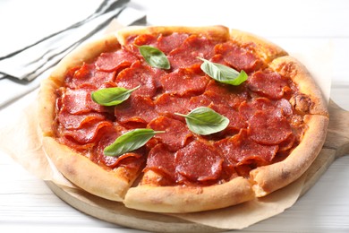 Photo of Tasty pepperoni pizza with basil on white wooden table