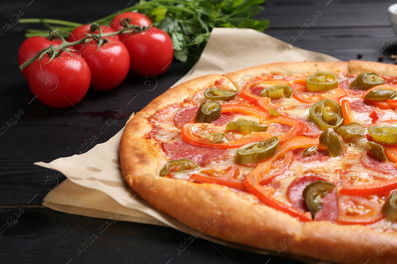 Photo of Delicious pizza Diablo and ingredients on black wooden table, closeup